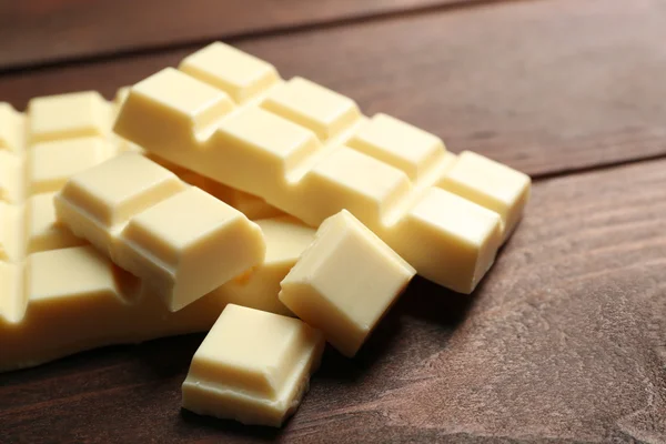 Pedaços de chocolate branco no fundo de madeira — Fotografia de Stock
