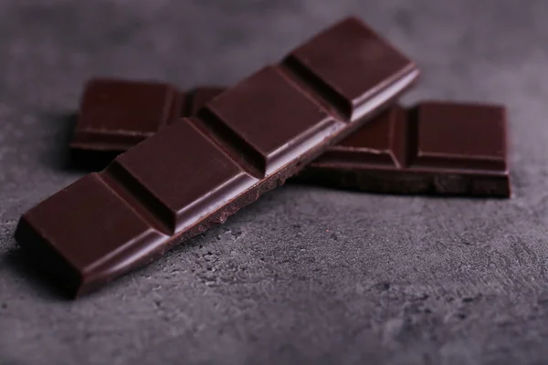 Piezas de chocolate negro sobre fondo gris oscuro —  Fotos de Stock