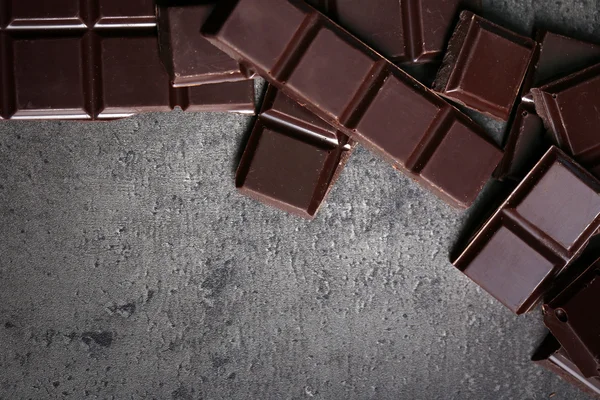 Morceaux de chocolat noir et grains de café sur fond gris foncé — Photo