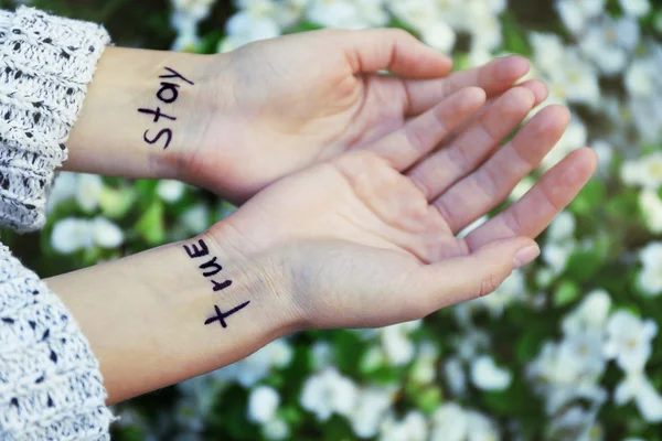Handen van jonge vrouw met getatoeëerd woorden — Stockfoto