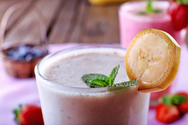 Vasos de batido frío fresco con frutas y bayas, sobre la mesa, primer plano — Foto de Stock