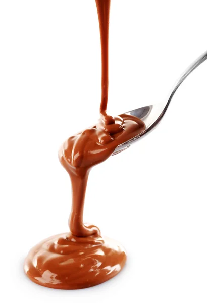 Geschmolzene milchige braune Schokolade aus einem Löffel, isoliert auf weiß — Stockfoto