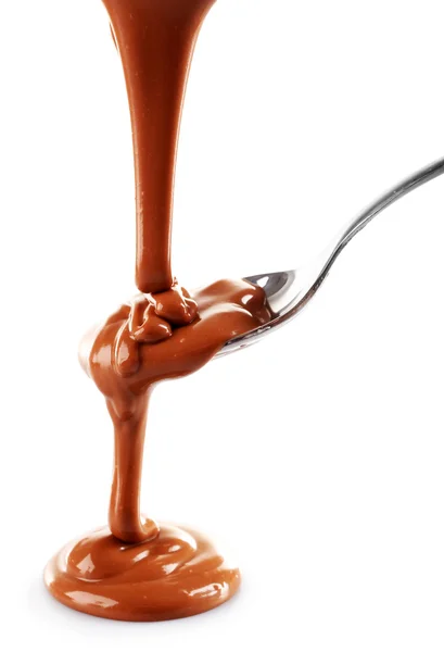 Melted milky brown chocolate pouring from a spoon, isolated on white — Stock Photo, Image