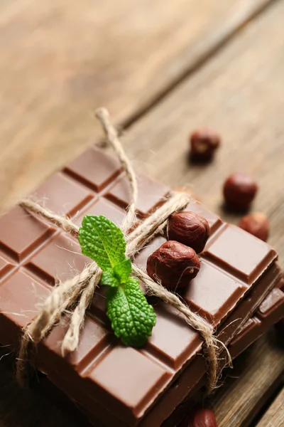 Black chocolate pieces with nuts on wooden background — Stock Photo, Image