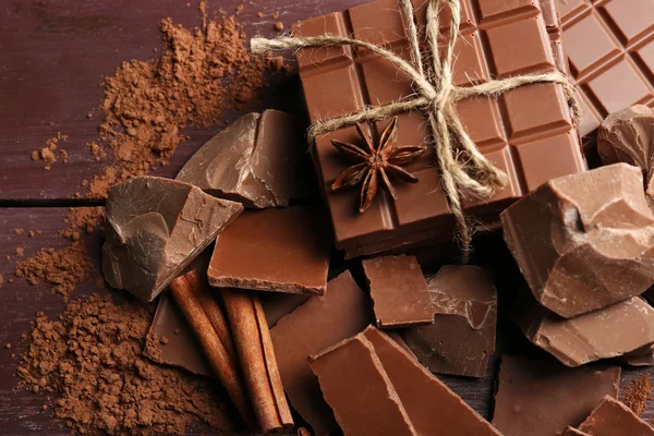 Части черного шоколада со специями на деревянном фоне — стоковое фото