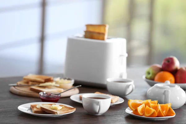 Tavola servita a colazione con pane tostato, caffè e frutta, su sfondo sfocato — Foto Stock