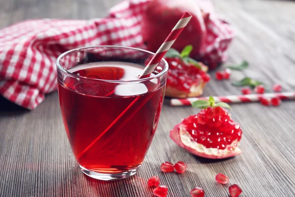 Sklenici chutné šťávy a granát ovoce, na dřevěné pozadí detail — Stock fotografie