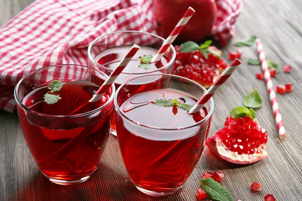 Three glasses of tasty juice and garnet fruit, on wooden background — Stock Photo, Image