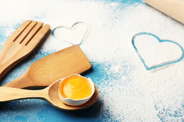 Coração de farinha e utensílios de cozinha de madeira no fundo azul — Fotografia de Stock