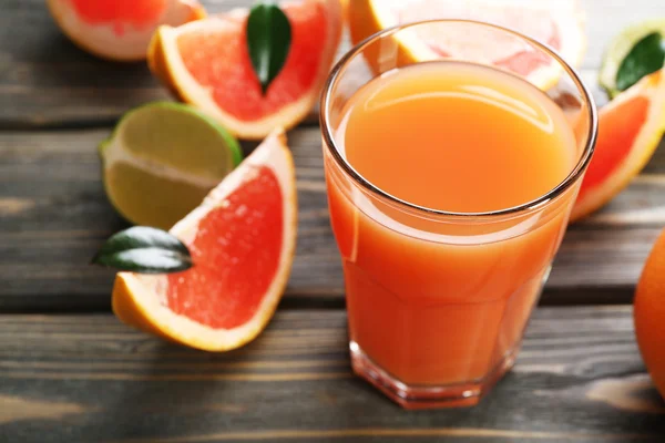 Verre de jus de pamplemousse et de fruits frais sur fond de bois — Photo