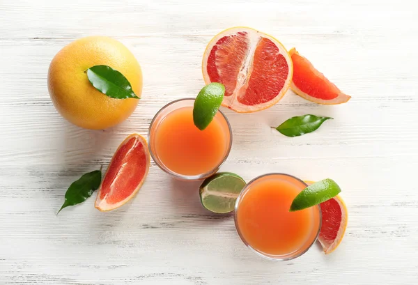 감귤 류의 주스와 가벼운 나무 배경에 신선한 과일의 두 잔 — 스톡 사진