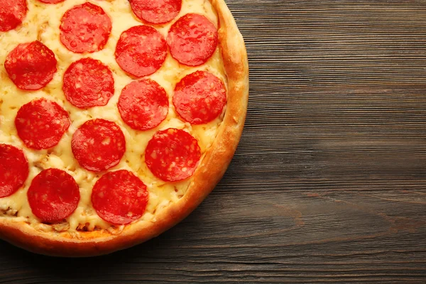 Pizza savoureuse avec salami sur fond bois, gros plan — Photo