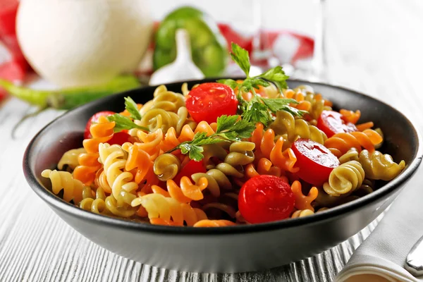 Delicioso plato de macarrones en tazón negro sobre mesa de madera gris servida — Foto de Stock