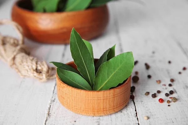 Hojas de laurel frescas en cuenco sobre mesa de madera blanca — Foto de Stock