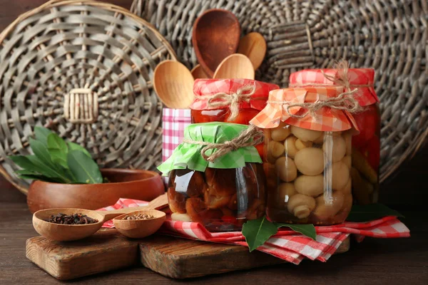 Jars with pickled vegetables and mushrooms on wooden background — Stock Photo, Image