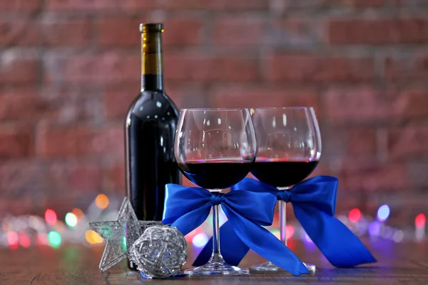 Rött vin och Christmas Ornament på träbord på vägg brick bakgrund med julbelysning — Stockfoto