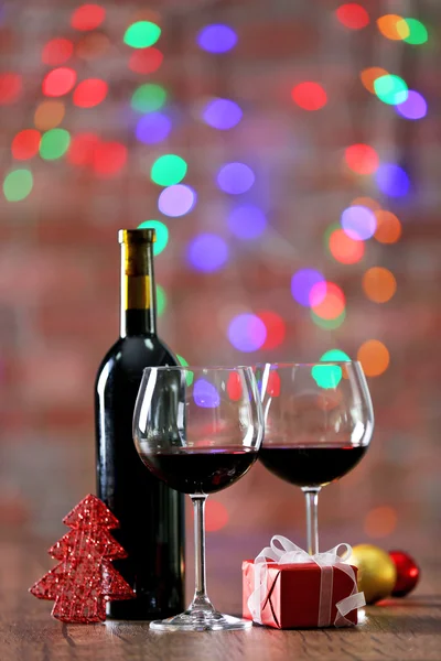 Vino tinto y adornos de Navidad en mesa de madera sobre fondo de luces de Navidad —  Fotos de Stock