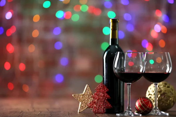 Vino rosso e ornamenti natalizi su tavola di legno su sfondo luci di Natale — Foto Stock
