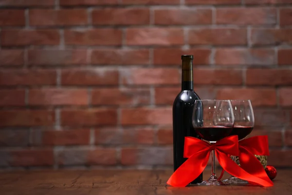 Κόκκινο κρασί και χριστουγεννιάτικα στολίδια στο ξύλινο τραπέζι σε φόντο τούβλο τοίχων — Φωτογραφία Αρχείου