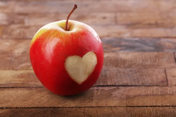 Яблоко с сердцем на деревянном столе — стоковое фото