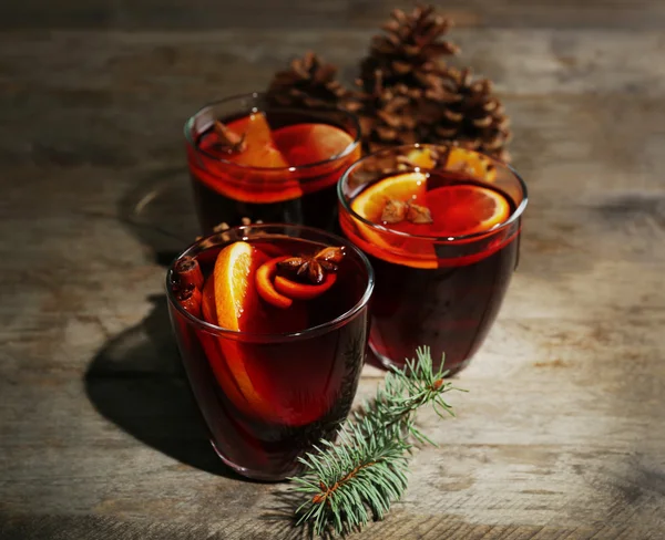 Mulled wine with spices and Christmas tree on wooden background — Stock Photo, Image