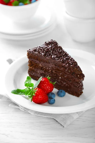 Chocolate cake met chocolade en verse bessen op plaat, op lichte achtergrond — Stockfoto