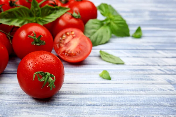 Fresh tomatoes with basil on wooden table close up — Stock Photo, Image