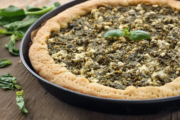 Open pie met spinazie op tafel close-up — Stockfoto