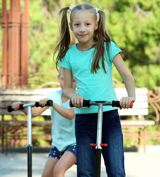 Kleine Mädchen fahren auf Rollern — Stockfoto