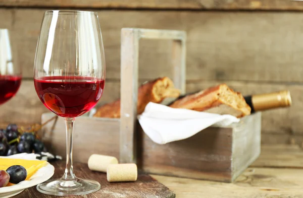 Natura morta di vino, uva, formaggio e pane su sfondo rustico in legno — Foto Stock