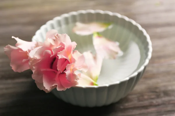 Inschrijving roze roos en bloemblaadjes in een kom — Stockfoto