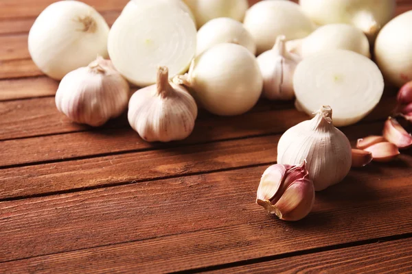 Fresh whole peeled onions with garlic on wooden background — Stock Photo, Image