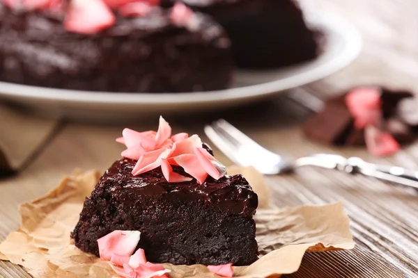 Pedazo de pastel de chocolate decorado con flores en la mesa de madera marrón — Foto de Stock