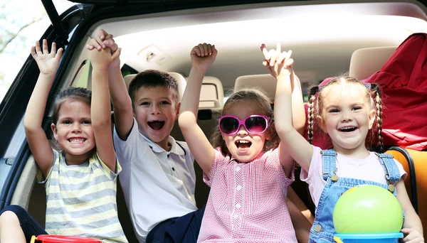 Meisjes en jongen zitten op de auto kofferbak — Stockfoto