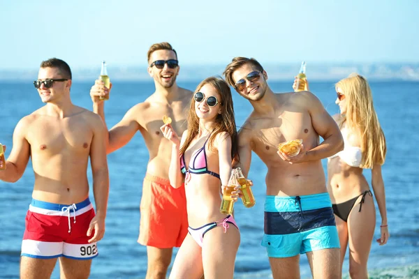 Happy přátelé pít pivo na pláži — Stock fotografie