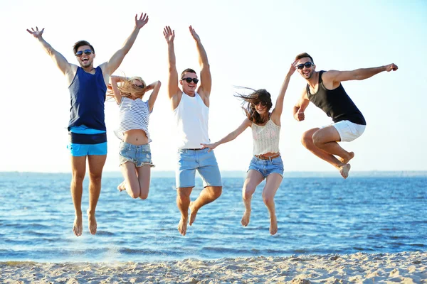 Amigos felizes pulando na praia — Fotografia de Stock