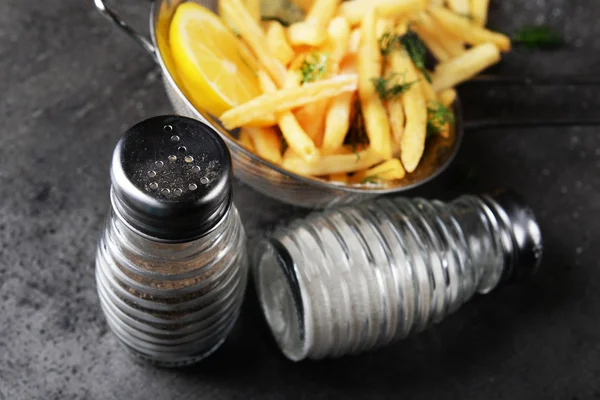 Franse frietjes met citroen en zout in zeef op tafel — Stockfoto