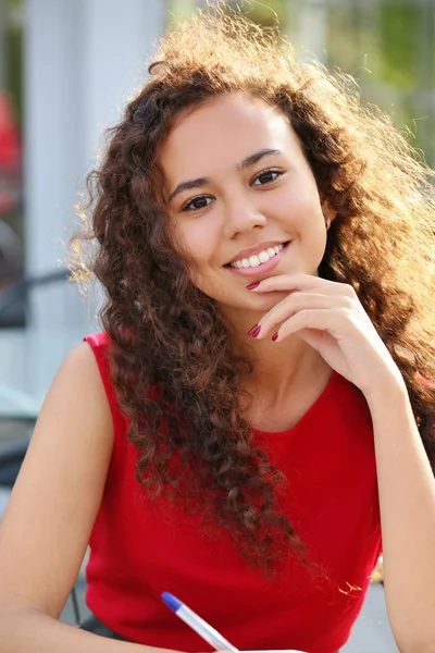 Mulher sorridente em vestido vermelho faz notação — Fotografia de Stock