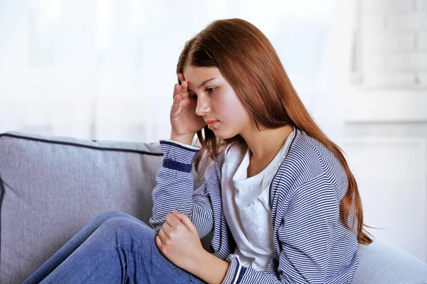 Menina perturbada sentado no sofá — Fotografia de Stock