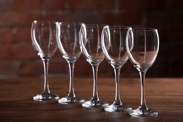 Пустые бокалы для вина на столе на фоне кирпичной стены — стоковое фото