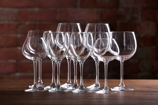 Empty wine glasses on a table on a brick wall background — Stock Photo, Image
