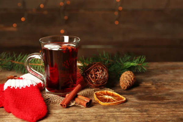 Christmas composition of mulled wine, cinnamon, pine and red knitted mittens on wooden table — Stock Photo, Image