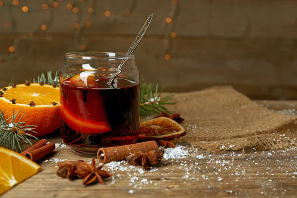 Mulled wine in glass bank on decorated wooden table — Stock Photo, Image