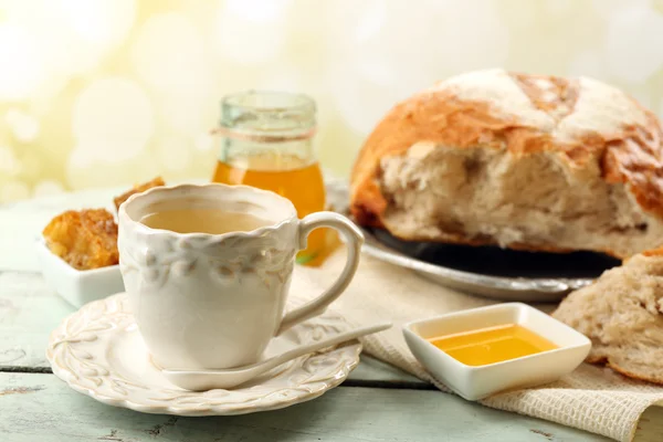 Favo de mel, tigela com mel, xícara com chá de ervas na tabela de madeira cor, no fundo claro — Fotografia de Stock