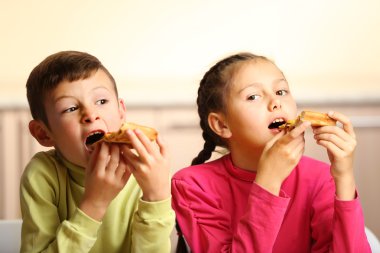 Çocuklar pizza yiyor.