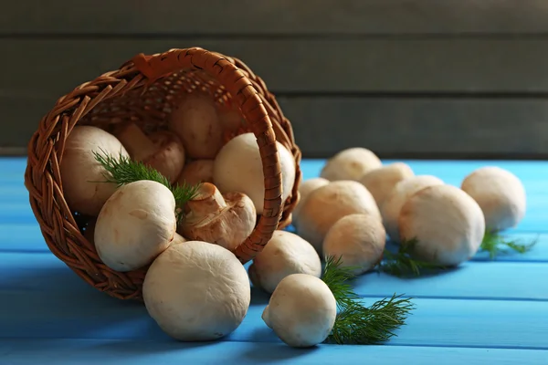 Paddestoelen in mand op kleur houten oppervlak — Stockfoto