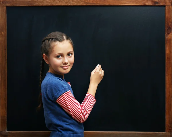 Leuk meisje die zich voordeed op de schone schoolbord — Stockfoto