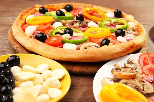 Delicious pizza and ingredients at the restaurant, close-up — Stock Photo, Image