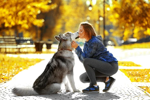 Kvinnan promenader med sin hund i park — Stockfoto