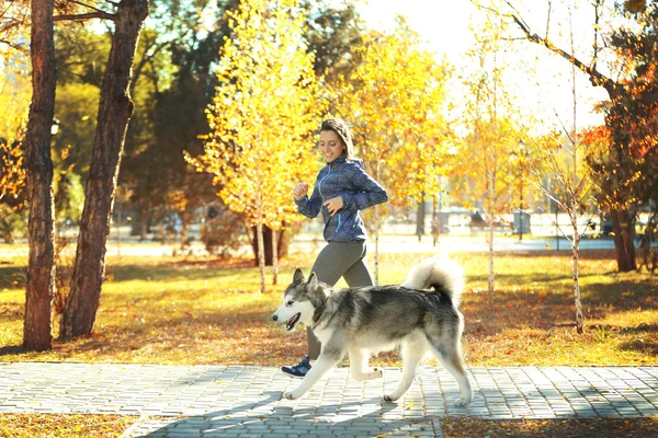 Vrouw joggen met haar hond in park — Stockfoto